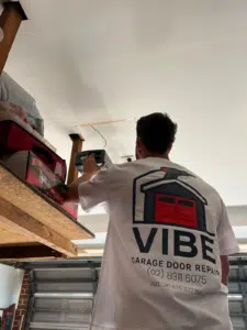 Technician from Vibe Garage Door Repair adjusting a garage door opener inside a residential garage in Sydney